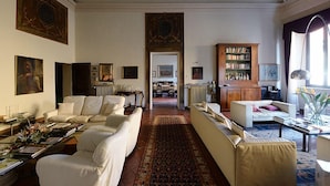 A spacious living room with a large window, a fireplace, and a bookshelf.