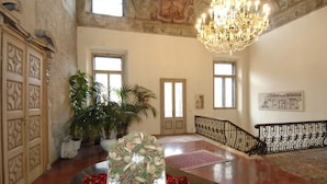 A grand hallway with a chandelier, potted plants, and a decorative table centerpiece.