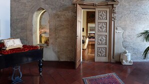 A room with a piano, a decorative door, and a stone statue.