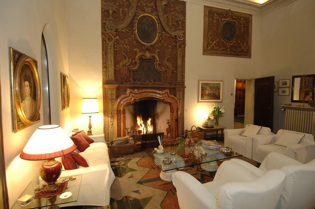 Una habitación tradicional con chimenea, muebles blancos y decoraciones ornamentales en las paredes.