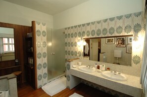 Un baño con dos lavamanos, un espejo grande y una ducha.