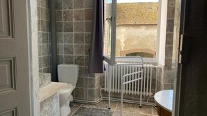 A bathroom with a toilet, a radiator, and a window.
