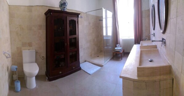 A bathroom with a toilet, a shower, a sink, and a cabinet.