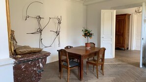 A dining area with a wooden table and chairs, a potted plant, and a marble side table. - Grand Corps de Ferme (Branches)