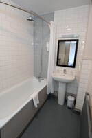 A modern bathroom with a white-tiled shower, a freestanding bathtub, a pedestal sink, and a mirror above the sink.