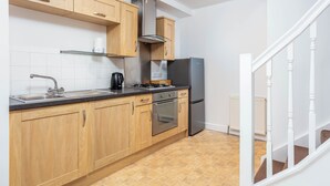 Eine moderne Küche mit Holzausstattung, Edelstahlgeräten und Fliesenboden.