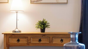 Ein Nachttisch aus Holz mit einer Lampe, einer Topfpflanze und einer Glasflasche.