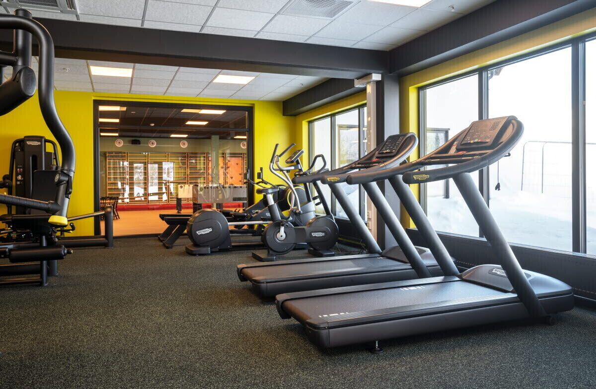 A gym with treadmills, weight machines, and a mirrored wall.
