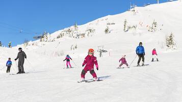 A ski slope with skiers and a ski lift in the background.
