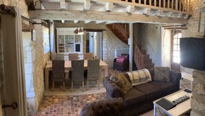 A rustic interior with a dining area, a sofa, and a staircase.
