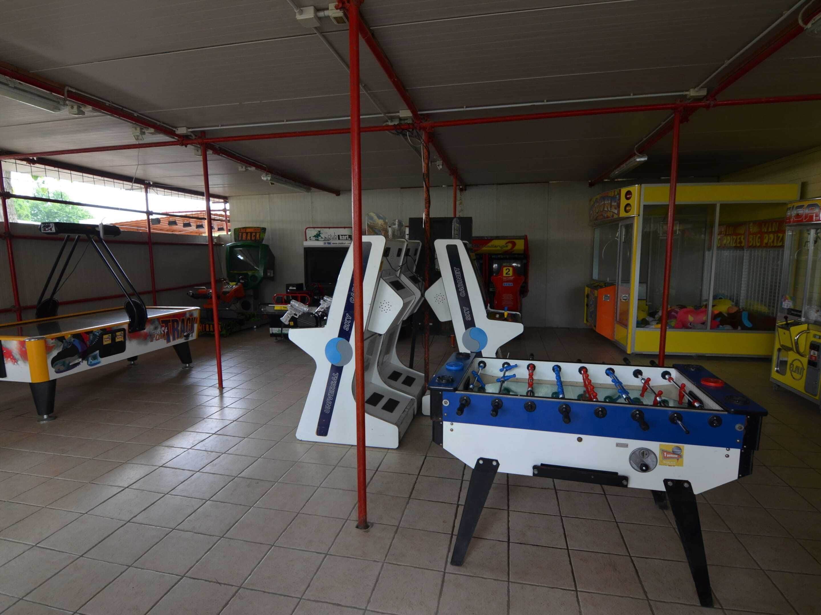 An indoor recreational area with foosball tables and arcade machines.