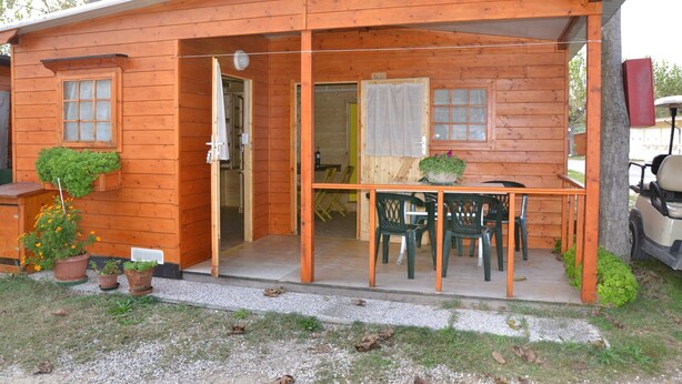 A wooden cabin with a porch, a table, and chairs. - Tidy Chalet with Terrace near Sea (Ravenna)