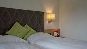 A hotel room with a large bed, two pillows, a nightstand with a lamp, and a wall-mounted light. - Holiday Flat Near Four ski Lifts in Mayrhofen (Schwendau)
