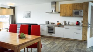 A modern kitchen with white cabinets, a wooden countertop, and a built-in microwave. - Apartment in Zell am See Near the ski Area (Zell am See)