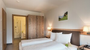 A hotel room with a large bed, a wooden headboard, a shower area, and a painting on the wall. - Apartment in Zell am See Near the ski Area (Zell am See)