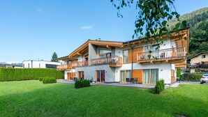 A modern two-story house with a balcony, a well-maintained lawn, and a mountain backdrop. - Apartment in Zell am See Near the ski Area (Zell am See)