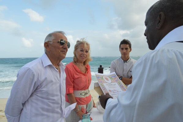 A group of people on a beach with a boat and a menu.