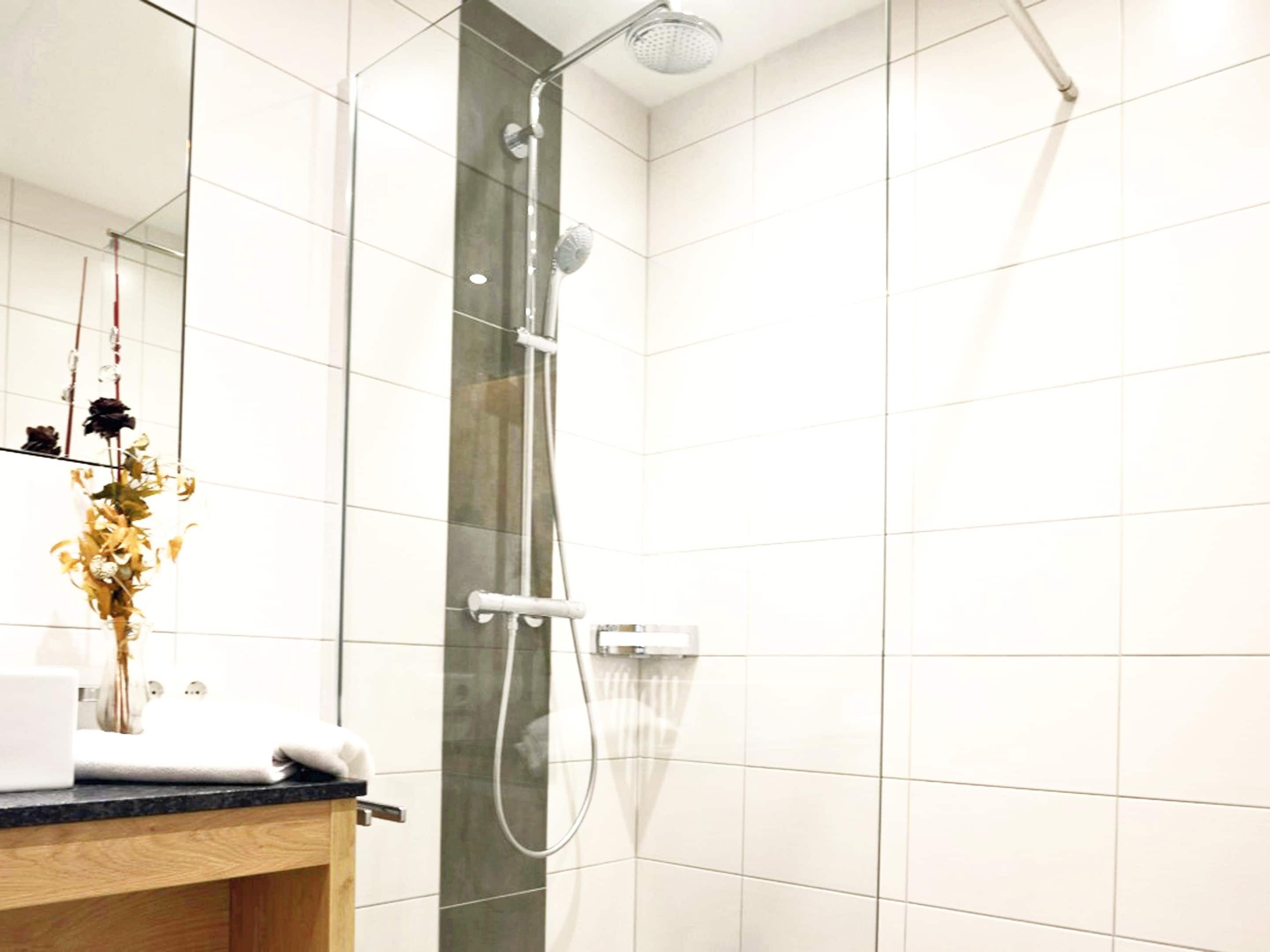A modern bathroom with a glass shower enclosure, a wooden vanity, and a mirror.