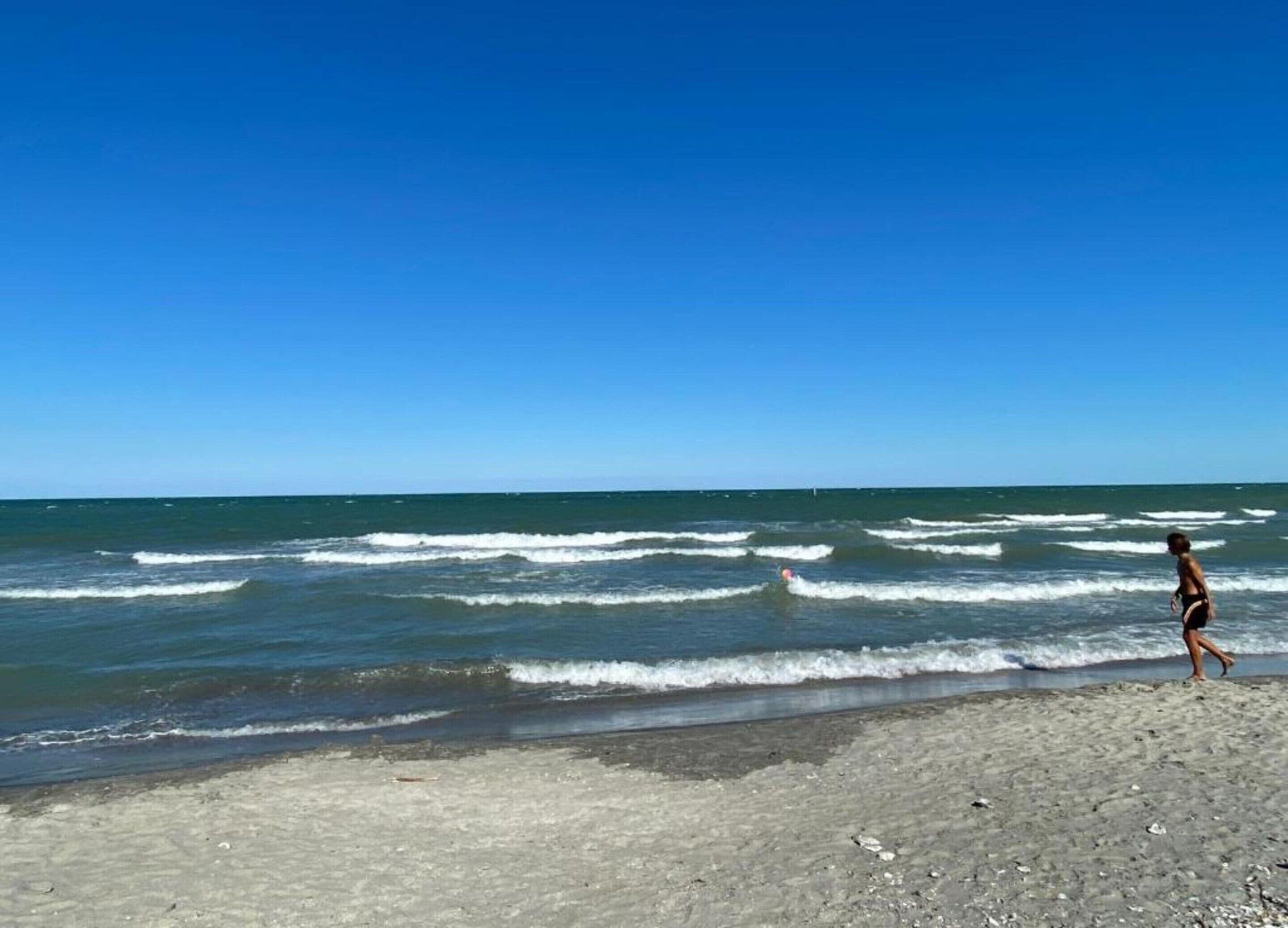 A beach with waves and a person walking.