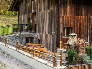 Un bâtiment rustique en bois, doté d’une terrasse et agrémenté d’éléments en pierre.