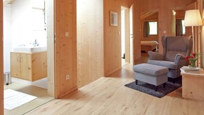 Un intérieur en bois avec un canapé, un pouf et une lampe sur une table d’appoint.