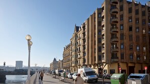 A waterfront promenade with buildings, street lamps, and parked vehicles. - Be Bop by FeelFree Rentals (Donostia)