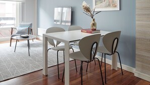 A dining area with a white table and chairs, a framed picture on the wall, and a window with a view. - Be Bop by FeelFree Rentals (Donostia)
