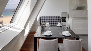 A dining area with a table set for four, a view of the beach, and a kitchen area. - Playa de La Concha 7 by FeelFree Rentals (Donostia)