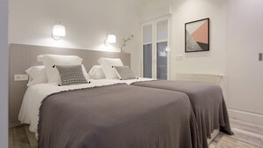 A modern bedroom with two beds, a large window, and a wall-mounted artwork. - Concha Bay 3 by FeelFree Rentals (Donostia)