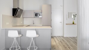 A modern kitchen with a central island, two white bar stools, and a microwave above the island. - Concha Bay 3 by FeelFree Rentals (Donostia)