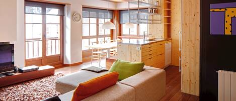 A modern living room with a sofa, a television, and a dining area.