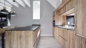 A modern kitchen with wooden cabinetry, a central island, pendant lighting, and a view of the adjacent living area. - Era Cuma by FeelFree Rentals (Pujo)