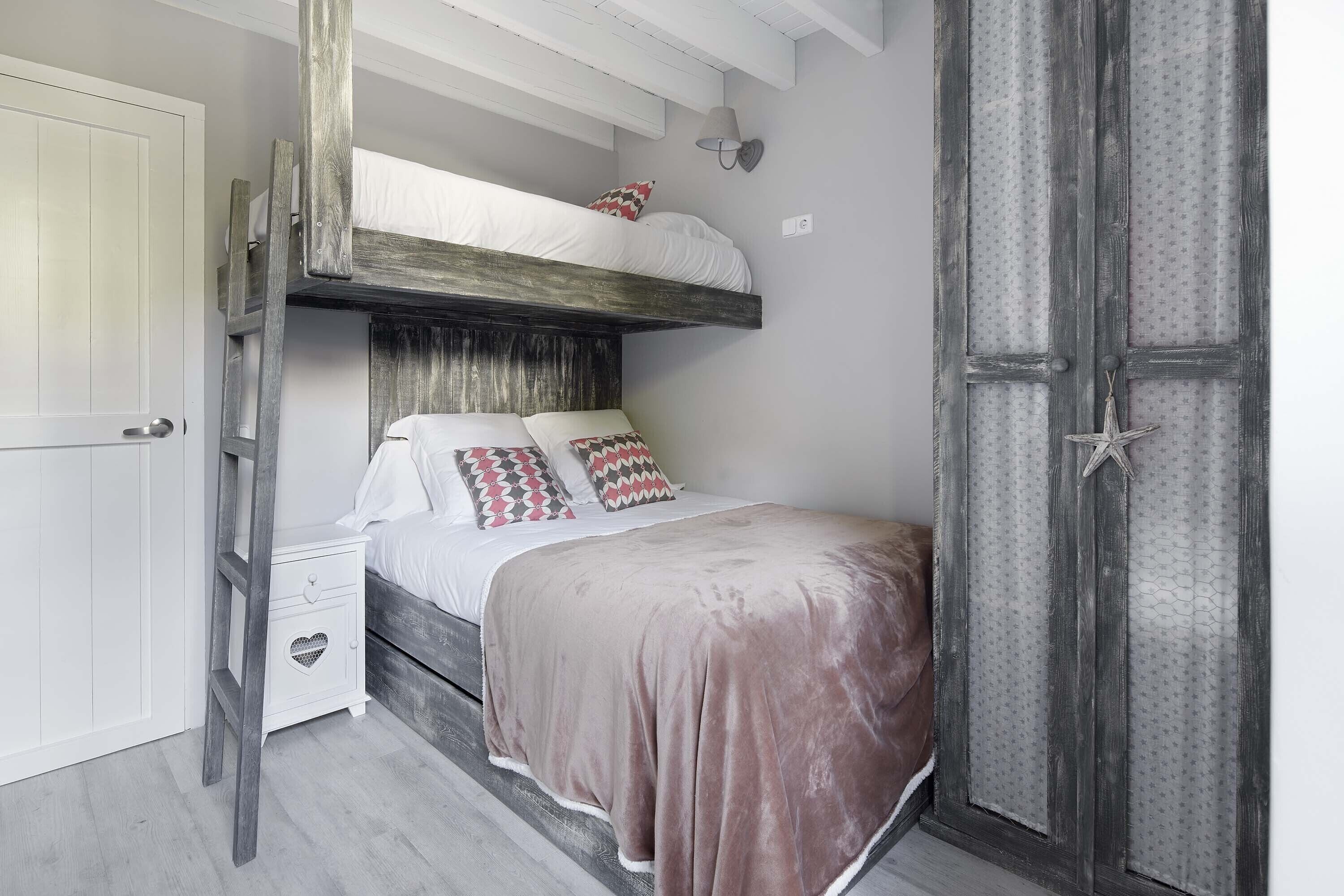 A bunk bed with a white headboard and a lower bunk with a wooden ladder.