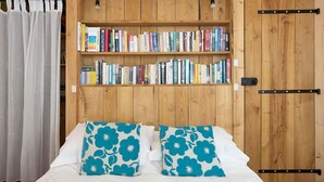A bedroom with a wooden wardrobe, a bookshelf with books, and a bed with floral pillows. - L'Atelier, a tranquil retreat with pool in its own valley 30 miles from the sea (Montferrer, Occitanie)