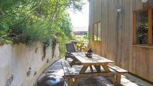 A wooden deck with a picnic table and a grill, surrounded by a stone wall and greenery. - L'Atelier, a tranquil retreat with pool in its own valley 30 miles from the sea (Montferrer, Occitanie)