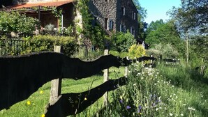 A stone building with a tiled roof, surrounded by lush greenery and a variety of flowers. - L'Atelier, a tranquil retreat with pool in its own valley 30 miles from the sea (Montferrer, Occitanie)