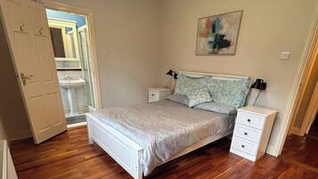 Un dormitorio con cama, mesitas de noche, lámpara de pared y un cuadro.
