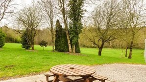 Une table de pique-nique en bois, avec des bancs, située dans un jardin.