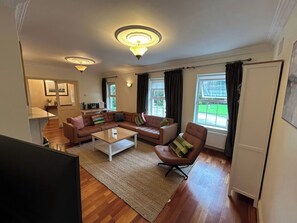 A living room with a sofa, armchair, coffee table, and a view of the outdoors. - The Sanctuary (Churchfield)