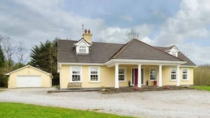 Une maison à deux étages avec un porche à l’avant, un garage et une allée gravillonnée.