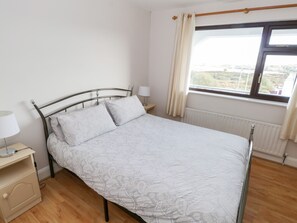 Cozy bedroom with a single bed, bedside table, and window offering a view of the outdoors.