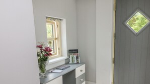 Habitación de esquina con escritorio, ventana, puerta y felpudo.