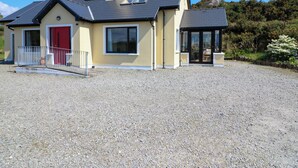 Una casa moderna con vialetto in ghiaia, una porta rossa e una veranda.
