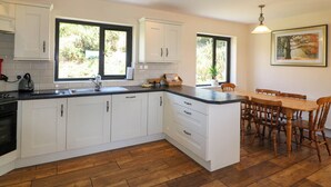 Una cucina moderna con mobili bianchi, un piano di lavoro nero e una zona pranzo con sedie in legno.
