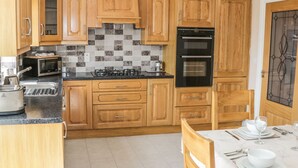Una cocina con armarios de madera, un horno negro, un microondas y una estufa a gas.