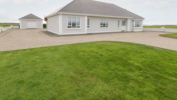 A two-story house with a gravel driveway and a well-maintained lawn.