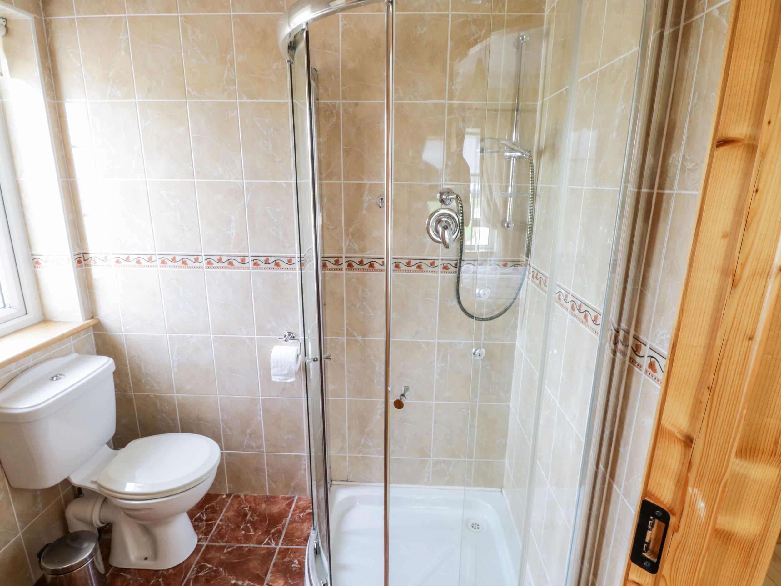 A bathroom with a glass-enclosed shower, a toilet, and a bathtub.