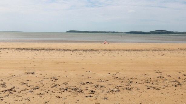 A wide sandy beach with a calm sea and distant hills. - Rose Cottage (Ramsgrange)