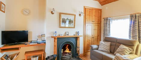 A cozy living room with a fireplace, a television, and a comfortable sofa.