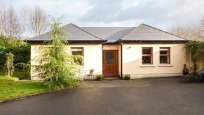 Une maison de plain-pied avec une porte d’entrée, deux fenêtres et un petit porche.